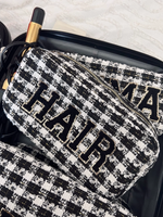 Picture of black and white tweed plaid make-up bag with varsity letter patches spelling out HAIR in black with gold trim