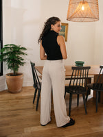 Girl wearing tailored wide leg trousers with front pleats in cement color.