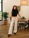 Girl wearing tailored wide leg trousers with front pleats in cement color.