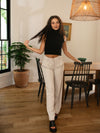 Girl wearing tailored wide leg trousers with front pleats in cement color.